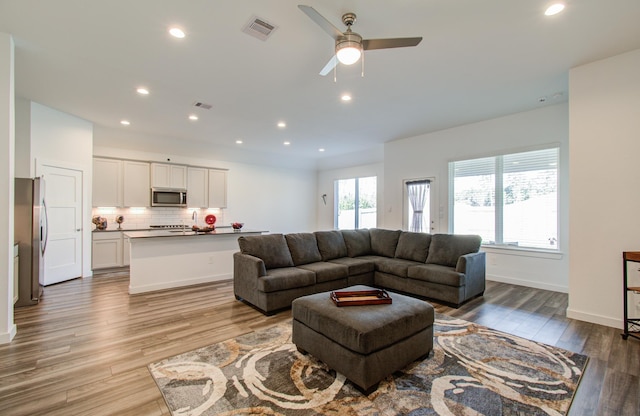 living room with a wealth of natural light, light hardwood / wood-style floors, and ceiling fan