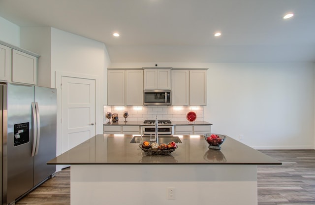 kitchen featuring stainless steel appliances, sink, a kitchen island with sink, and wood-type flooring