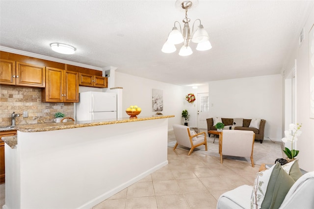 kitchen with sink, light stone countertops, decorative backsplash, decorative light fixtures, and white fridge