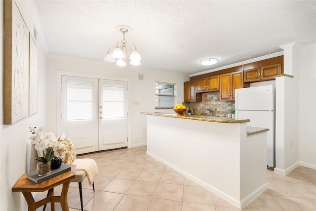 kitchen featuring a textured ceiling, ornamental molding, white fridge, pendant lighting, and decorative backsplash