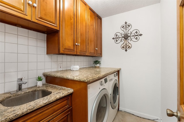 washroom featuring light tile patterned flooring, sink, cabinets, washer and dryer, and a textured ceiling