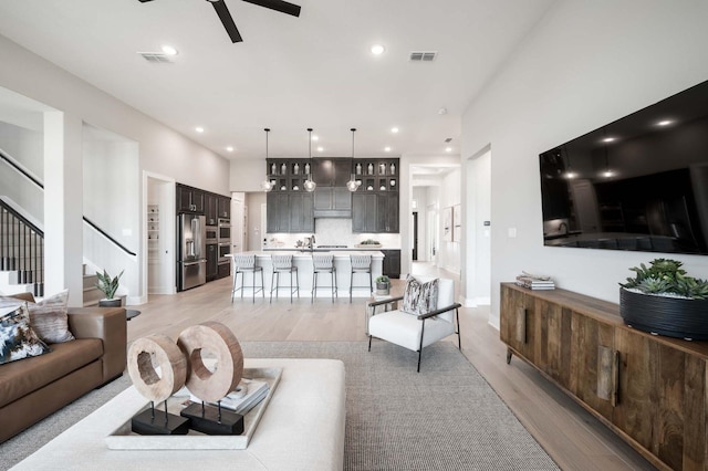 living area featuring visible vents, light wood-style floors, and stairs