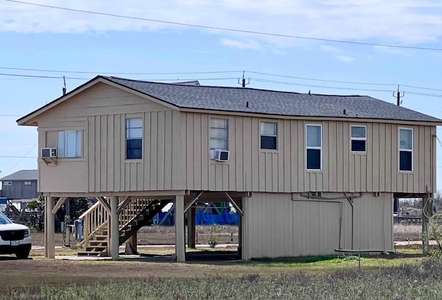 exterior space with a carport, stairway, and roof with shingles