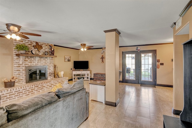 living room featuring ornate columns, ceiling fan, crown molding, a brick fireplace, and french doors