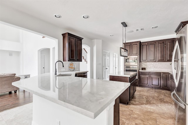 kitchen with pendant lighting, sink, appliances with stainless steel finishes, backsplash, and a center island