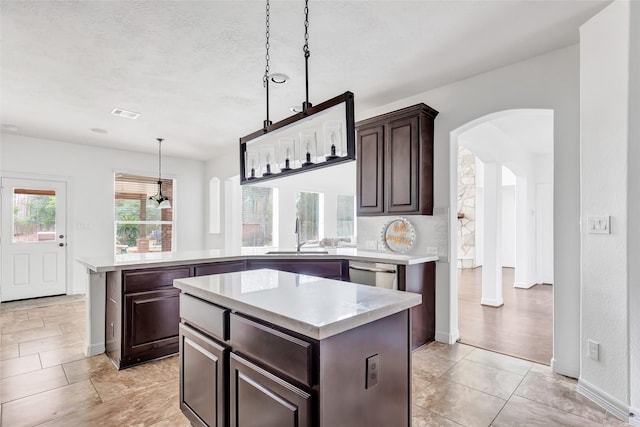 kitchen featuring pendant lighting, dark brown cabinets, a center island, and dishwasher