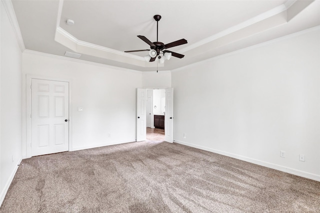 carpeted spare room featuring ceiling fan, ornamental molding, and a tray ceiling