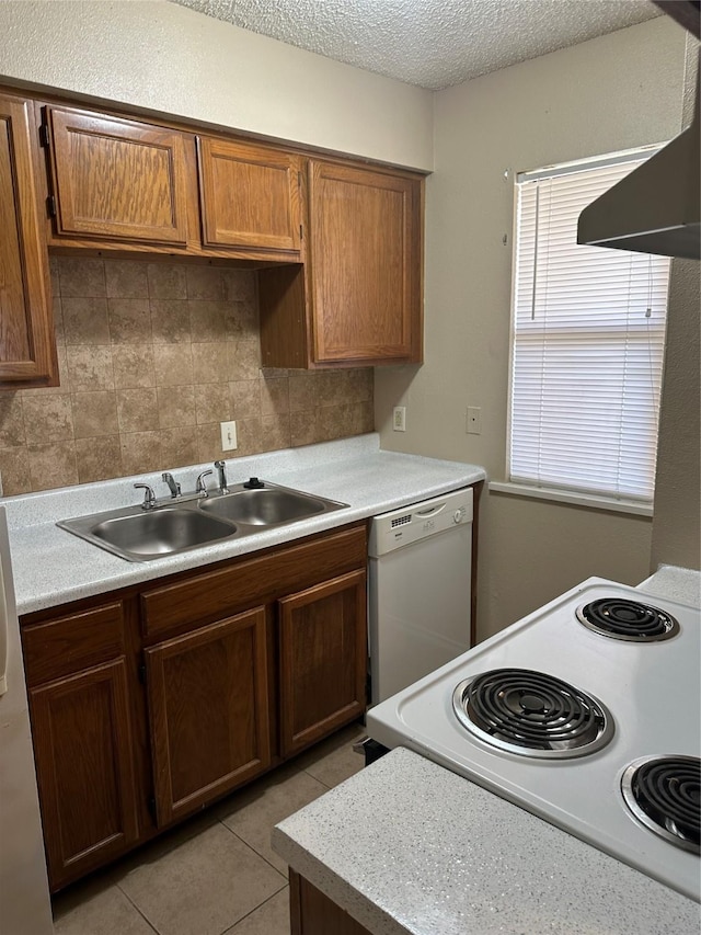 kitchen with sink, a textured ceiling, light tile patterned floors, white appliances, and backsplash