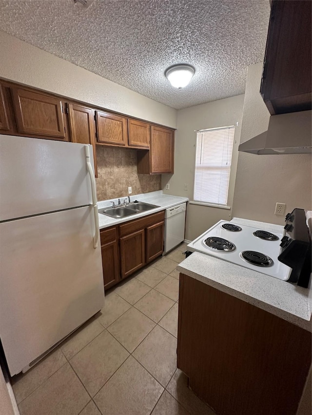 kitchen with light tile patterned flooring, sink, ventilation hood, a textured ceiling, and white appliances