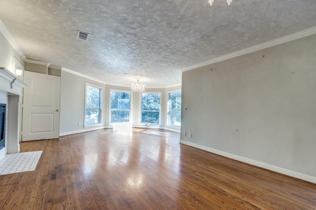 unfurnished living room with a tiled fireplace, crown molding, and an inviting chandelier