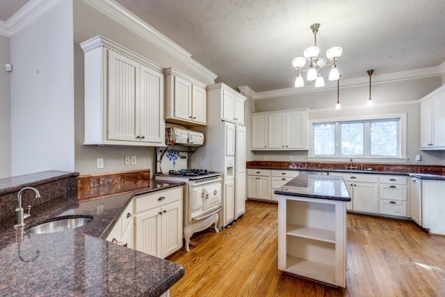 kitchen featuring white cabinetry, sink, dark stone countertops, hanging light fixtures, and a center island