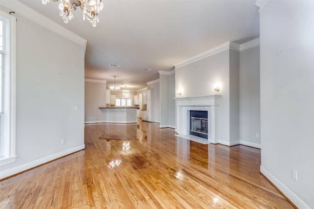 36111 Post Oak Cir, Magnolia, TX 77355 - unfurnished living room featuring a chandelier, ornamental molding, light wood-style floors, and a fireplace