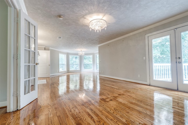 36111 Post Oak Cir, Magnolia, TX 77355 - unfurnished room with a chandelier, french doors, ornamental molding, light wood-style flooring, and a textured ceiling