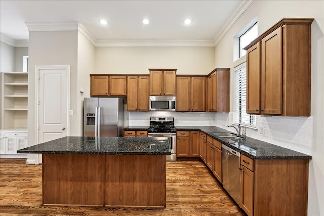 kitchen featuring a kitchen island, appliances with stainless steel finishes, sink, dark stone counters, and crown molding