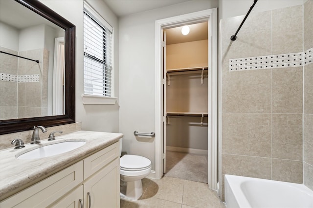 full bathroom featuring tile patterned flooring, vanity, tiled shower / bath, and toilet