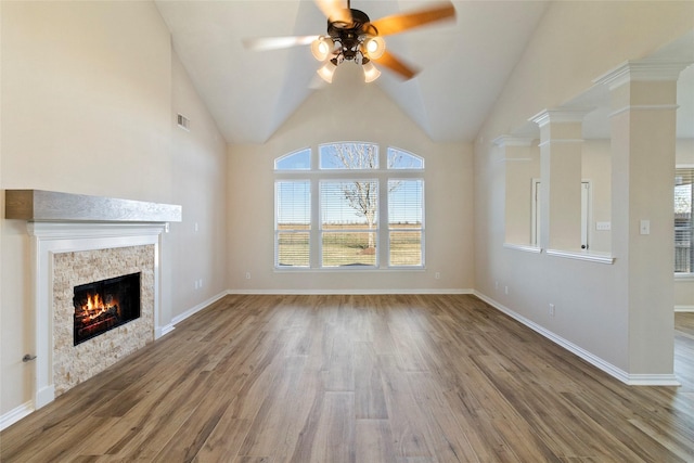 unfurnished living room featuring lofted ceiling, ornate columns, ceiling fan, a fireplace, and hardwood / wood-style floors