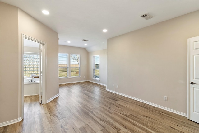 unfurnished room featuring lofted ceiling and light hardwood / wood-style floors