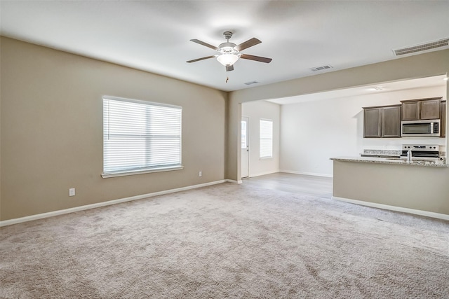 unfurnished living room featuring light colored carpet and ceiling fan