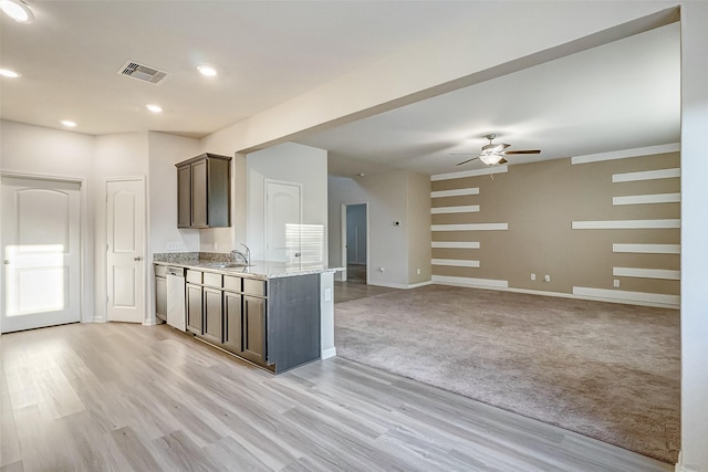 kitchen featuring sink, ceiling fan, dark brown cabinetry, light stone counters, and stainless steel dishwasher