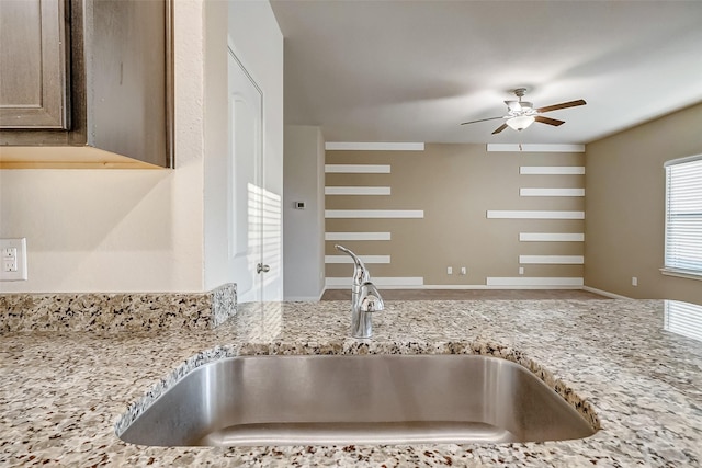 kitchen with sink, light stone countertops, and ceiling fan