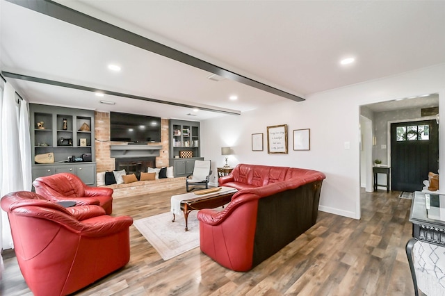 living area featuring a brick fireplace, wood finished floors, beam ceiling, and baseboards