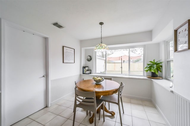 dining room with light tile patterned floors, visible vents, and wainscoting