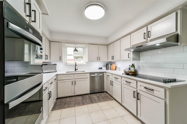 kitchen featuring under cabinet range hood, a sink, light countertops, appliances with stainless steel finishes, and tasteful backsplash