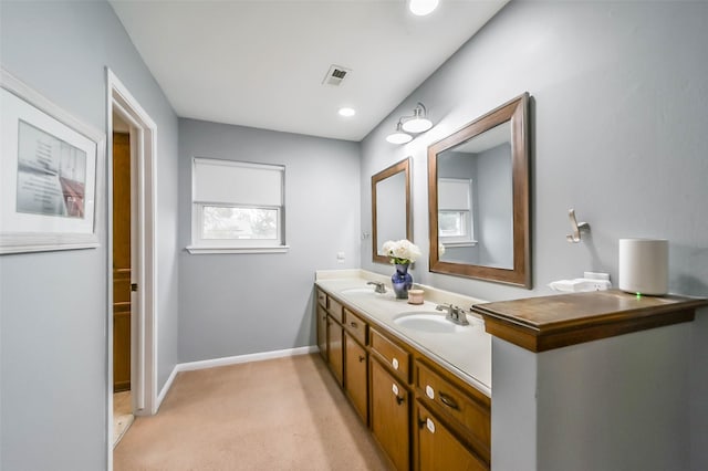 bathroom featuring double vanity, a sink, visible vents, and baseboards