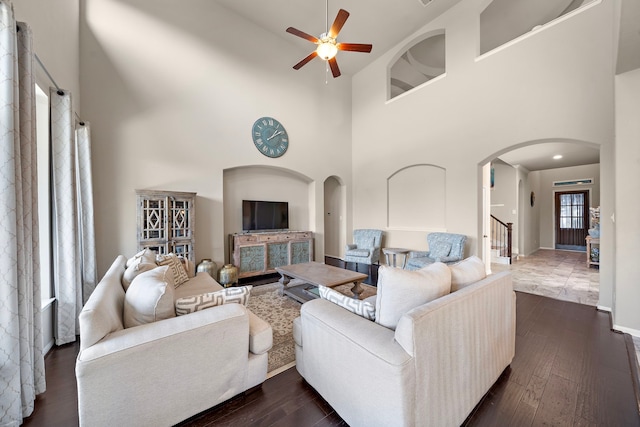 living room featuring dark hardwood / wood-style floors, ceiling fan, and a high ceiling