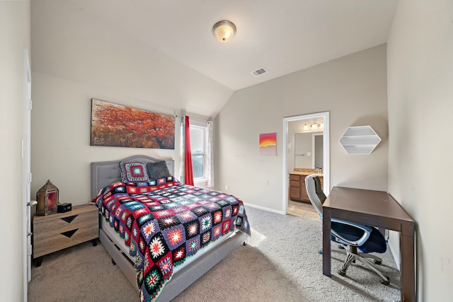 bedroom with connected bathroom, vaulted ceiling, and light carpet