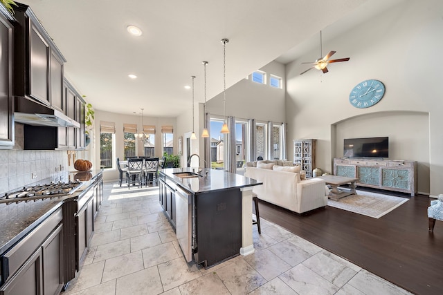 kitchen with sink, a breakfast bar, tasteful backsplash, a center island with sink, and decorative light fixtures