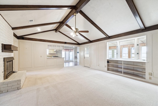 unfurnished living room featuring light colored carpet, a healthy amount of sunlight, lofted ceiling with beams, and a brick fireplace