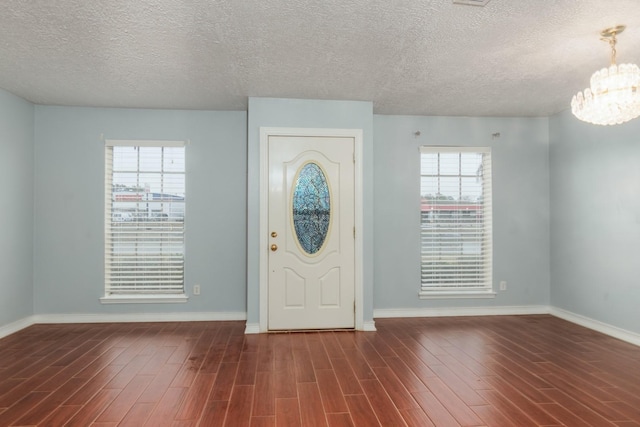 entryway featuring dark hardwood / wood-style floors, a textured ceiling, and a notable chandelier