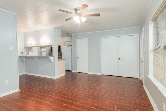 unfurnished living room with crown molding, ceiling fan, hardwood / wood-style floors, and a textured ceiling