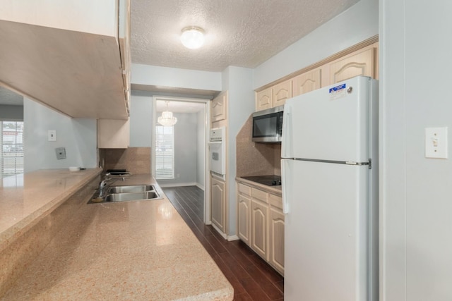 kitchen featuring white appliances, dark wood-type flooring, a textured ceiling, light brown cabinetry, and a sink