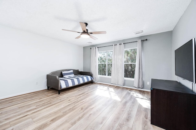 unfurnished bedroom with ceiling fan, a textured ceiling, and light wood-type flooring