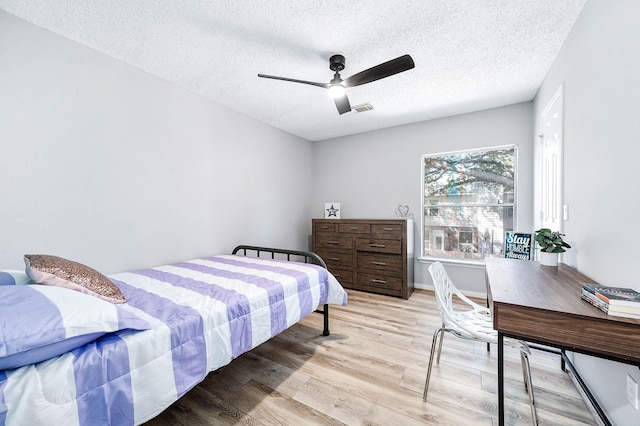 bedroom with a textured ceiling, ceiling fan, and light wood-type flooring