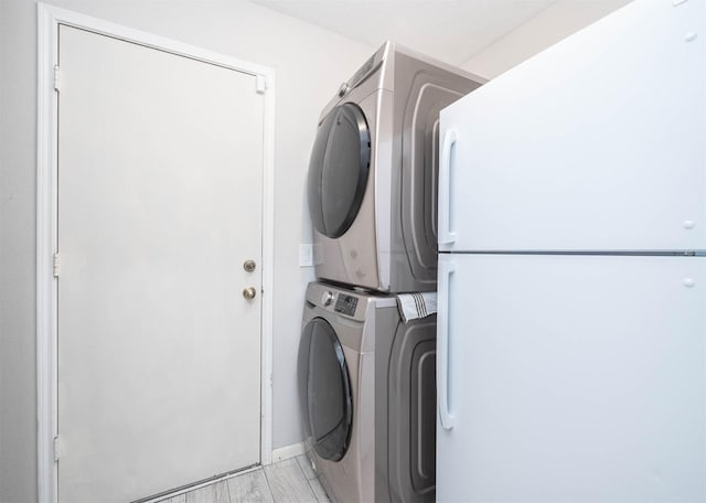 washroom with stacked washer and dryer and light hardwood / wood-style floors