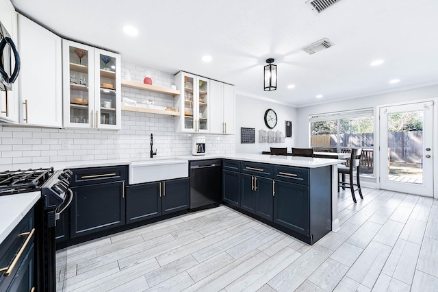 kitchen featuring sink, white cabinetry, tasteful backsplash, kitchen peninsula, and black appliances