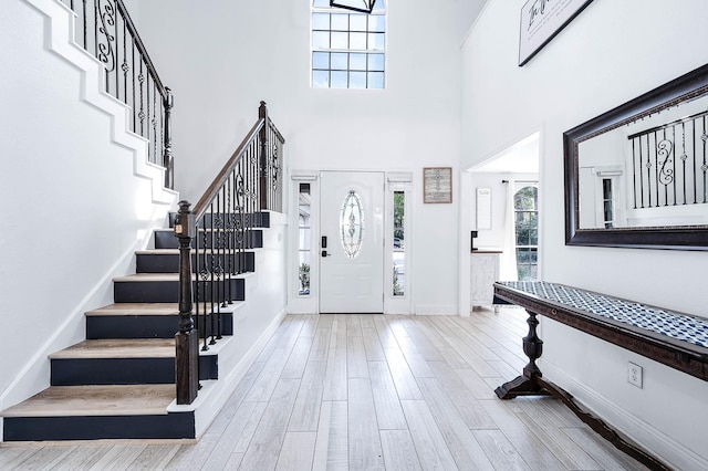 entryway featuring a towering ceiling and light wood-type flooring