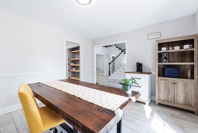 dining room featuring built in shelves and light wood-type flooring