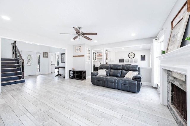 living room featuring a tile fireplace, ceiling fan, and light hardwood / wood-style flooring