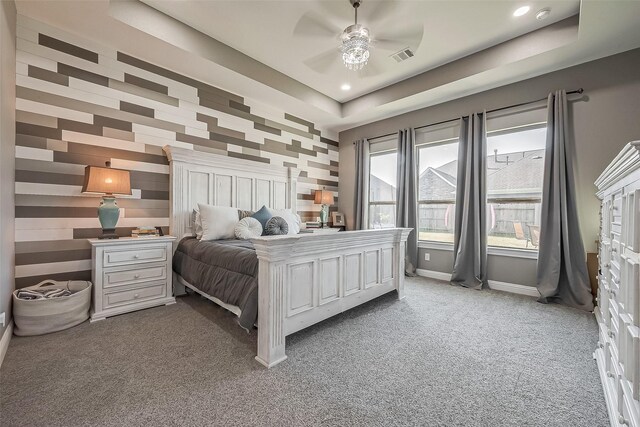 bedroom with a tray ceiling, carpet floors, and ceiling fan