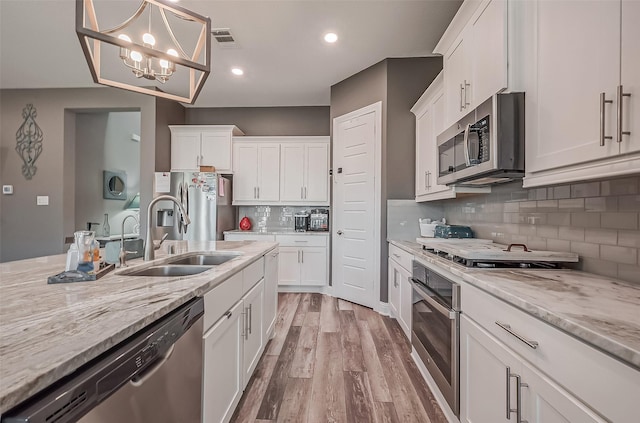 kitchen with white cabinetry, sink, stainless steel appliances, and hanging light fixtures