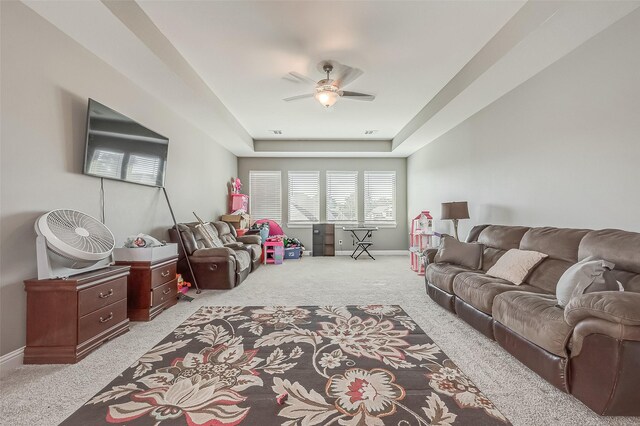 living room featuring light colored carpet, ceiling fan, and a tray ceiling