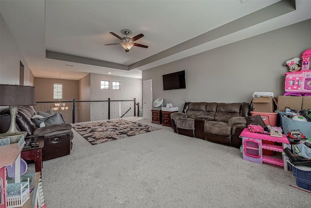 carpeted living room with a raised ceiling and ceiling fan