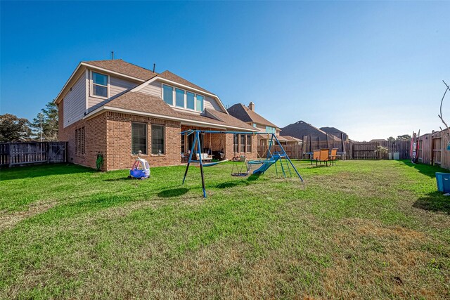 rear view of property featuring a playground and a lawn