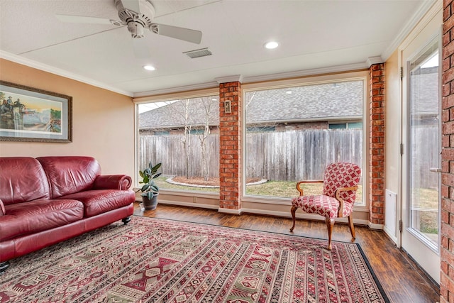 living room with crown molding, a healthy amount of sunlight, and dark hardwood / wood-style flooring