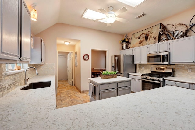 kitchen with lofted ceiling, sink, appliances with stainless steel finishes, ceiling fan, and backsplash