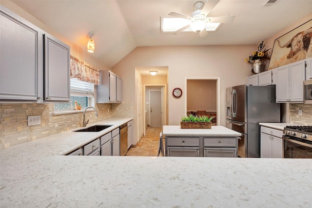 kitchen with gray cabinets, appliances with stainless steel finishes, lofted ceiling, sink, and decorative backsplash